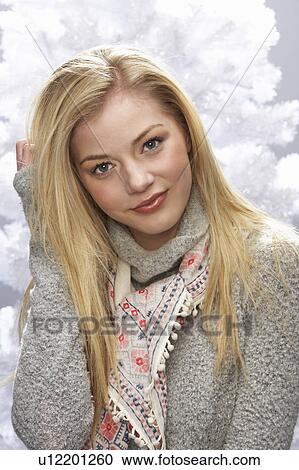 Stock Image - Fashionable Teenage Girl Wearing Cap And Knitwear In Studio In Front Of Christmas Tree. Fotosearch