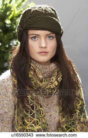 Stock Image - Fashionable Teenage Girl Wearing Cap And Knitwear In Studio In Front Of Christmas Tree. Fotosearch