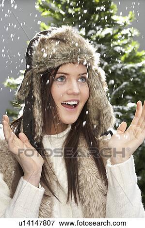 Stock Photo - Fashionable Teenage Girl Wearing Cap And Knitwear In Studio In Front Of Christmas Tree. Fotosearch