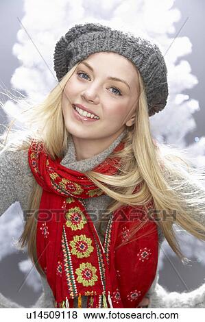 Stock Photo - Fashionable Teenage Girl Wearing Cap And Knitwear In Studio In Front Of Christmas Tree. Fotosearch