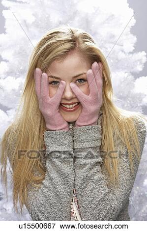 Stock Photo - Fashionable Teenage Girl Wearing Cap And Knitwear In Studio In Front Of Christmas Tree. Fotosearch