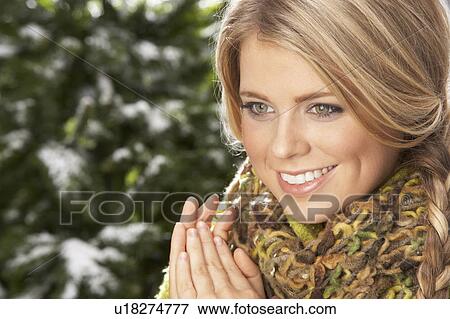 Stock Photo - Fashionable Woman Wearing Knitwear And Scarf In Studio In Front Of Christmas Tree. Fotosearch