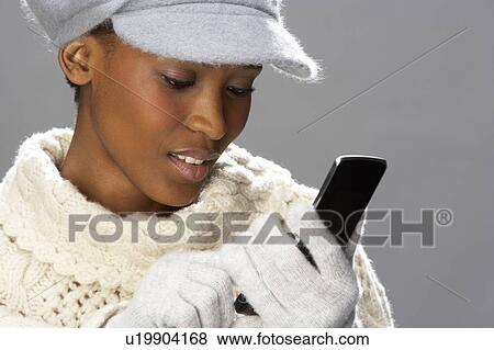 Fashionable Woman Wearing Knitwear And Cap In Studio Using Mobile Phone View Large Photo Image Stock Photo - Fashionable Woman Wearing Knitwear And Cap In Studio Using Mobile Phone. Fotosearch