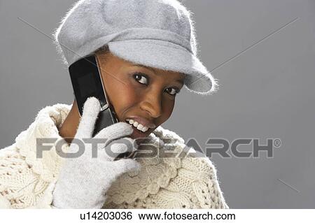 Fashionable Woman Wearing Knitwear And Cap In Studio Using Mobile Phone View Large Photo Image Stock Photograph - Fashionable Woman Wearing Knitwear And Cap In Studio Using Mobile Phone. Fotosearch