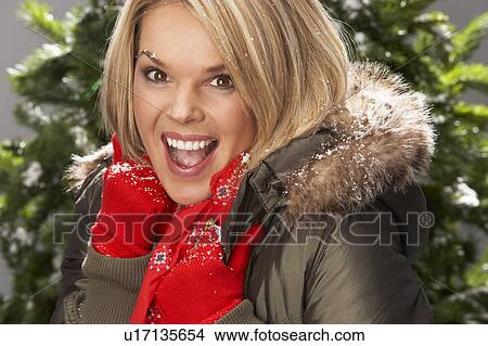 Picture - Fashionable Woman Wearing Parka Coat And Scarf In Studio In Front Of Christmas Tree. Fotosearch