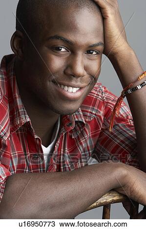 Stock Image - Fashionable Young Resting On Chair Man Wearing Casual Clothes In Studio. Fotosearch