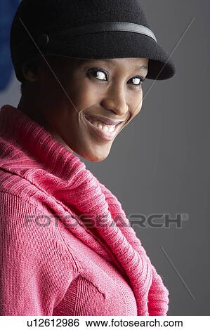 Stock Photograph - Fashionable Young Woman Wearing Cap And Knitwear In Studio. Fotosearch
