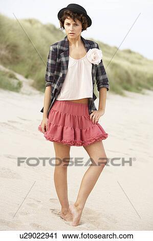 Stock Image - Fashionably Dressed Attractive Young Woman Standing Amongst Sand Dunes. Fotosearch