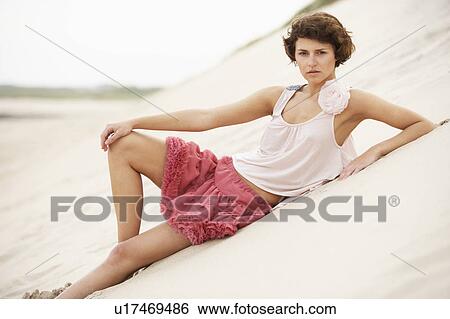 Stock Photograph - Fashionably Dressed Attractive Young Woman Standing Amongst Sand Dunes. Fotosearch