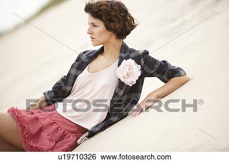 Stock Photograph - Fashionably Dressed Attractive Young Woman Standing Amongst Sand Dunes. Fotosearch