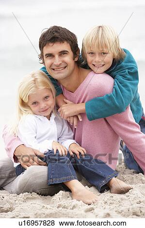 Stock Photo - Father And Children Sitting On Winter Beach Together. Fotosearch