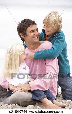 Stock Photograph - Father And Children Sitting On Winter Beach Together. Fotosearch