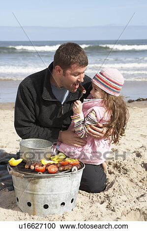 Stock Image - Father And Daughter Having Barbeque On Winter Beach. Fotosearch