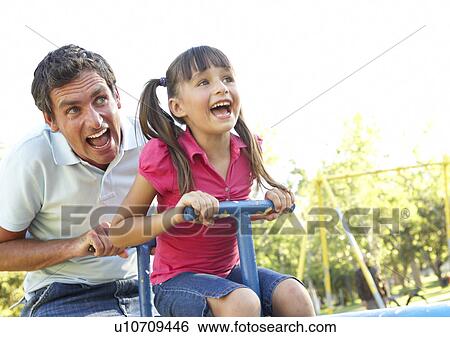 Stock Photograph - Father And Daughter Riding On See Saw In Playground. Fotosearch