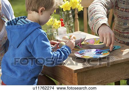 Picture - Father And Son Decorating Easter Eggs On Table Outdoors . Fotosearch