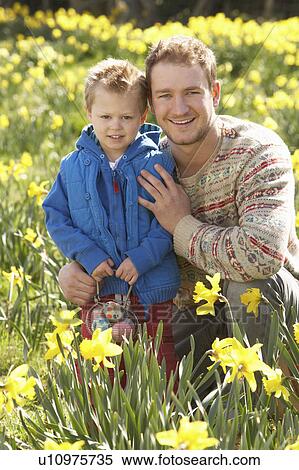 Stock Photography - Father And Son On Easter Egg Hunt In Daffodil Field. Fotosearch