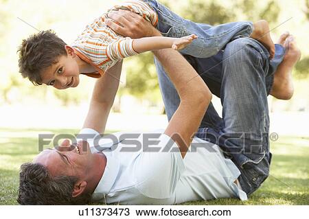 Stock Image - Father And Son Playing Together In Park. Fotosearch