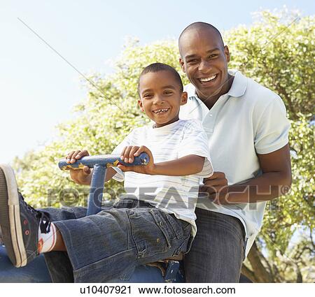 Father and Son Riding On SeeSaw In Park View Large Photo Image Stock Image - Father and Son Riding On SeeSaw In Park. Fotosearch