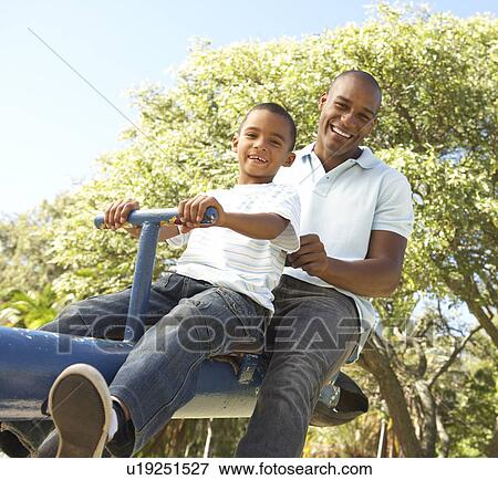 Father and Son Riding On SeeSaw In Park View Large Photo Image Stock Photo - Father and Son Riding On SeeSaw In Park. Fotosearch