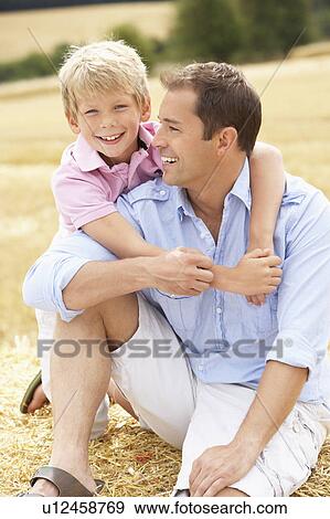 Father And Son Sitting On Straw Bales In Harvested Field View Large Photo Image Stock Photo - Father And Son Sitting On Straw Bales In Harvested Field. Fotosearch