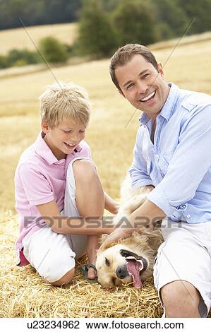 Father And Son Sitting With Dog On Straw Bales In Harvested Field View Large Photo Image Stock Image - Father And Son Sitting With Dog On Straw Bales In Harvested Field. Fotosearch