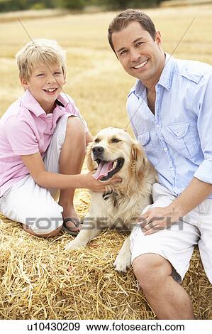 Father And Son Sitting With Dog On Straw Bales In Harvested Field View Large Photo Image Stock Photo - Father And Son Sitting With Dog On Straw Bales In Harvested Field. Fotosearch