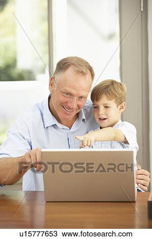Stock Image - Father And Son Using Laptop At Home. Fotosearch