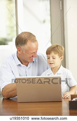 Stock Image - Father And Son Using Laptop At Home. Fotosearch