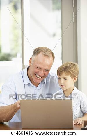 Stock Photograph - Father And Son Using Laptop At Home. Fotosearch
