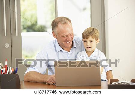 Stock Photograph - Father And Son Using Laptop At Home. Fotosearch