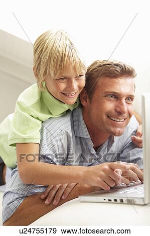 Stock Photo - Father And Son Using Laptop Relaxing Sitting On Sofa At Home. Fotosearch