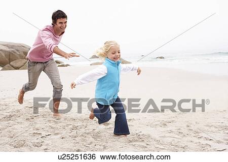 Stock Photograph - Father Chasing Daughter Along Winter Beach. Fotosearch