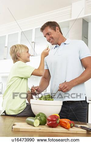 Stock Image - Father & Son Preparing Salad In Modern Kitchen. Fotosearch