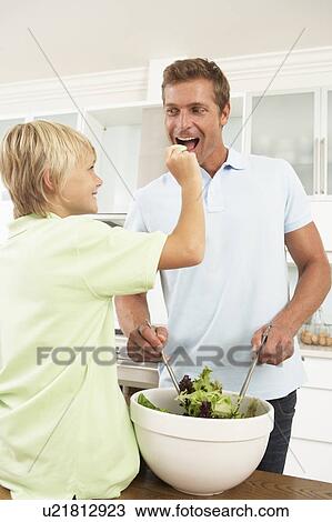 Stock Image - Father & Son Preparing Salad In Modern Kitchen. Fotosearch