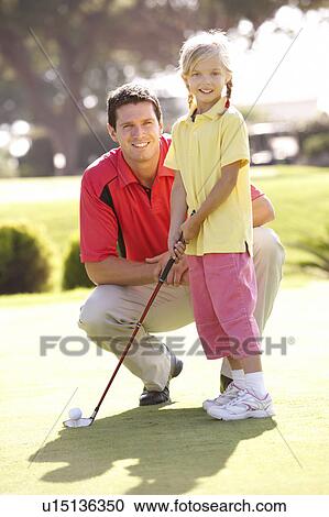 Stock Image - Father Teaching Daughter To Play Golf On Putting On Green. Fotosearch