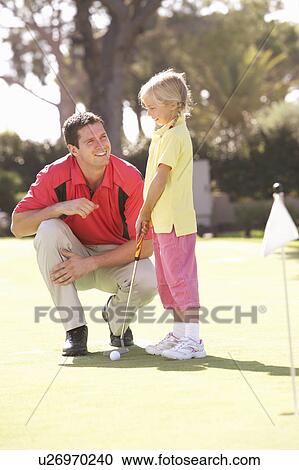Stock Image - Father Teaching Daughter To Play Golf On Putting On Green. Fotosearch