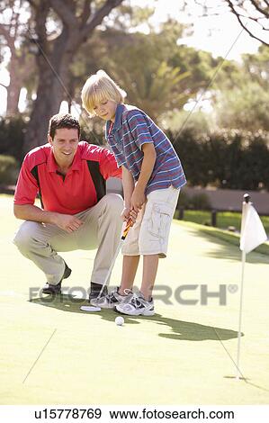 Stock Photo - Father Teaching Son To Play Golf On Putting On Green. Fotosearch