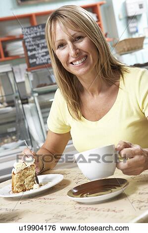 Stock Photograph - Female Customer Enjoying Slice Of Cake And Coffee In Café . Fotosearch
