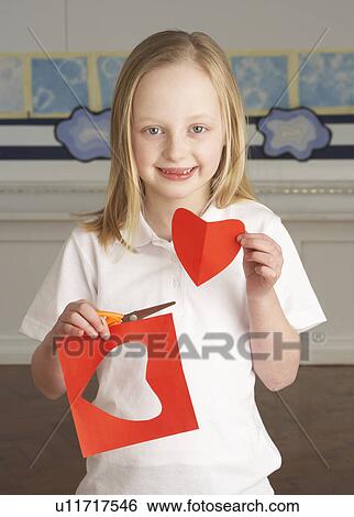 Stock Photograph - Female Primary School Pupil Cutting Out Paper Shapes In Craft Lesson. Fotosearch