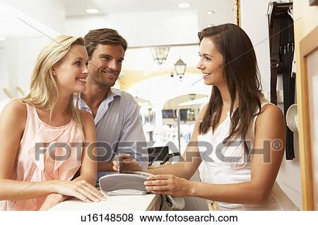 Female Sales Assistant At Checkout Of Clothing Store With Customers View Large Photo Image Stock Photo - Female Sales Assistant At Checkout Of Clothing Store With Customers. Fotosearch