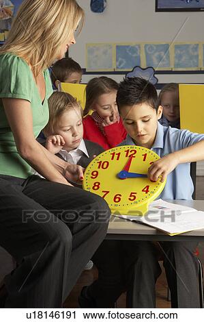Female Teacher In Primary School Teaching Children To Tell Time In Classroom View Large Photo Image Stock Image - Female Teacher In Primary School Teaching Children To Tell Time In Classroom. Fotosearch