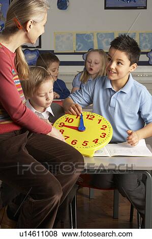 Female Teacher In Primary School Teaching Children To Tell Time In Classroom View Large Photo Image Stock Photo - Female Teacher In Primary School Teaching Children To Tell Time In Classroom. Fotosearch