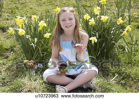 Girl Eating Chocolate Egg On Easter Egg Hunt In Daffodil Field View Large Photo Image Stock Image - Girl Eating Chocolate Egg On Easter Egg Hunt In Daffodil Field. Fotosearch