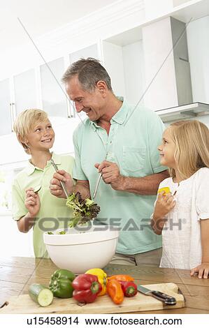 Picture - Grandchildren Helping Grandfather To Prepare Salad In Modern Kitchen. Fotosearch
