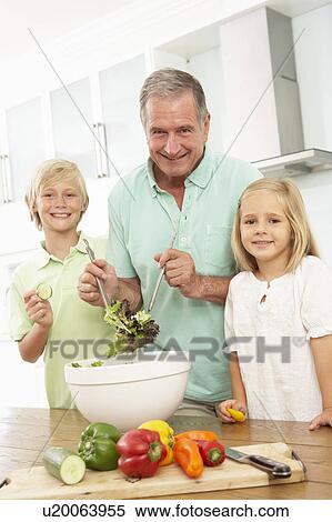 Stock Photography - Grandchildren Helping Grandfather To Prepare Salad In Modern Kitchen. Fotosearch