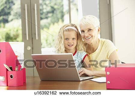 Stock Image - Granddaughter And Grandmother Using Laptop At Home. Fotosearch
