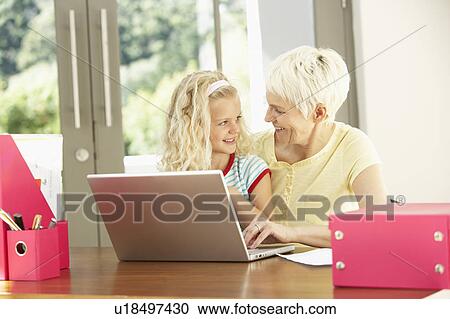 Stock Image - Granddaughter And Grandmother Using Laptop At Home. Fotosearch