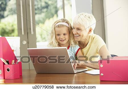 Stock Photo - Granddaughter And Grandmother Using Laptop At Home. Fotosearch