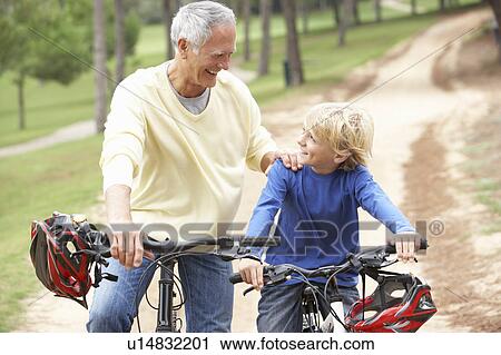 Grandfather and grandson riding bicycle in park View Large Photo Image Stock Image - Grandfather and grandson riding bicycle in park. Fotosearch