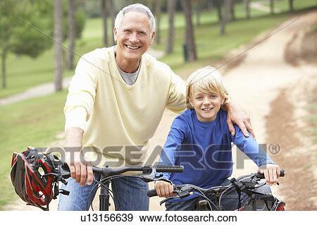 Stock Photo - Grandfather and grandson riding bicycle in park. Fotosearch